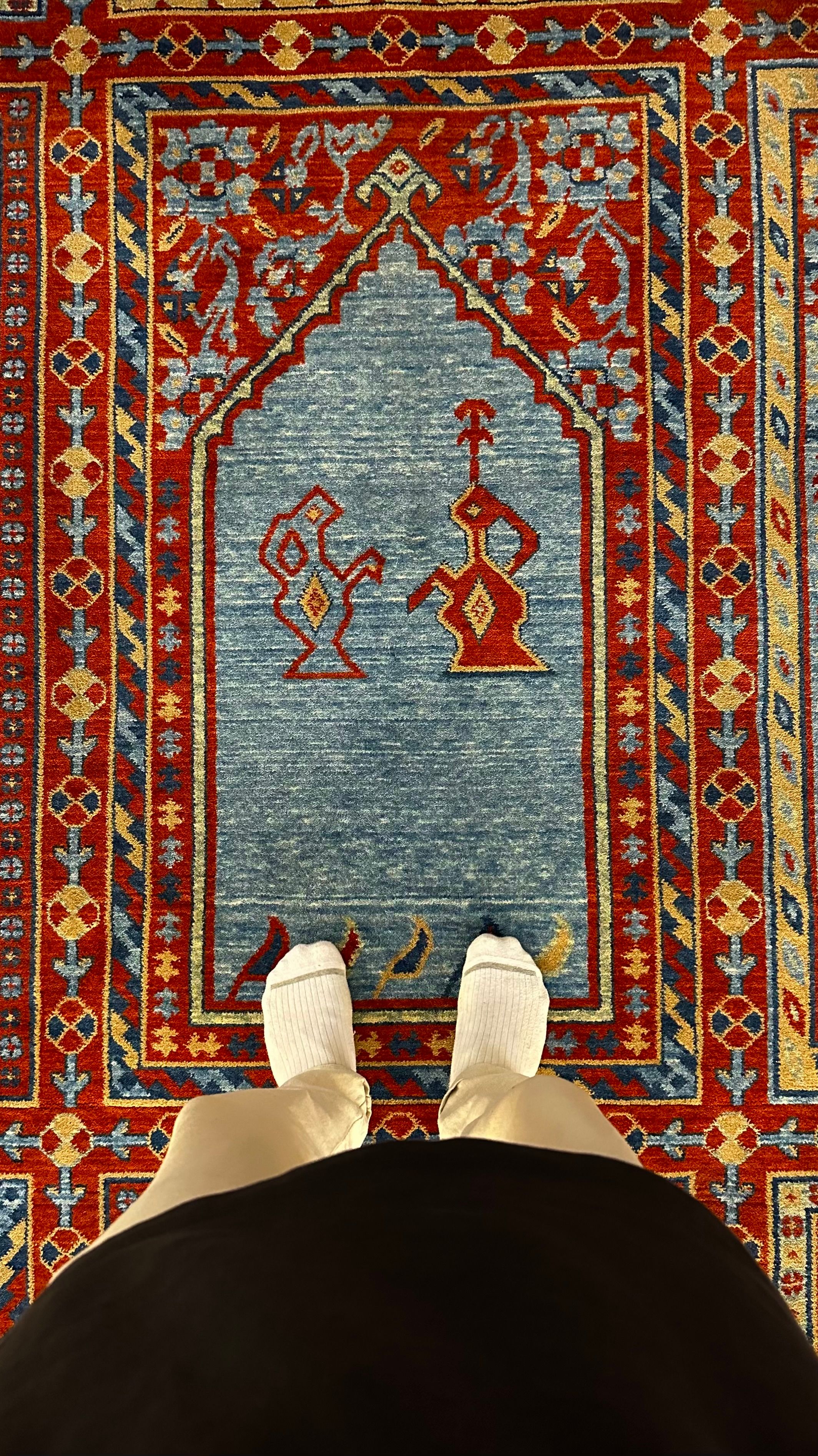 A person standing on an intricately designed colorful carpet, showcasing traditional patterns.