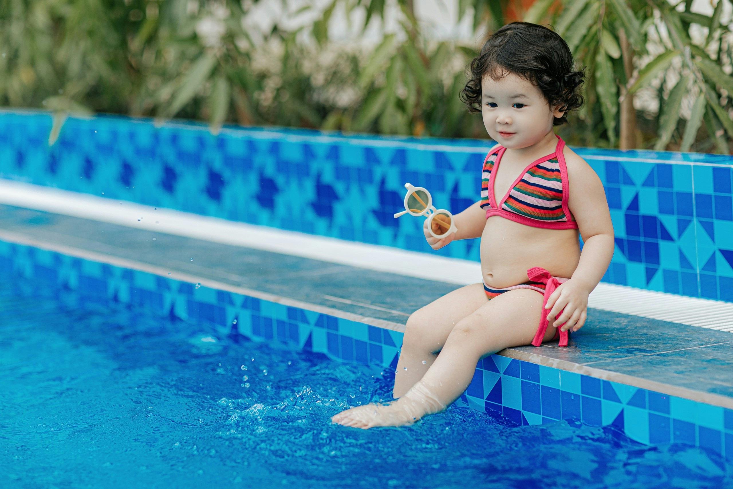 Toddler girl sitting safely by pool edge