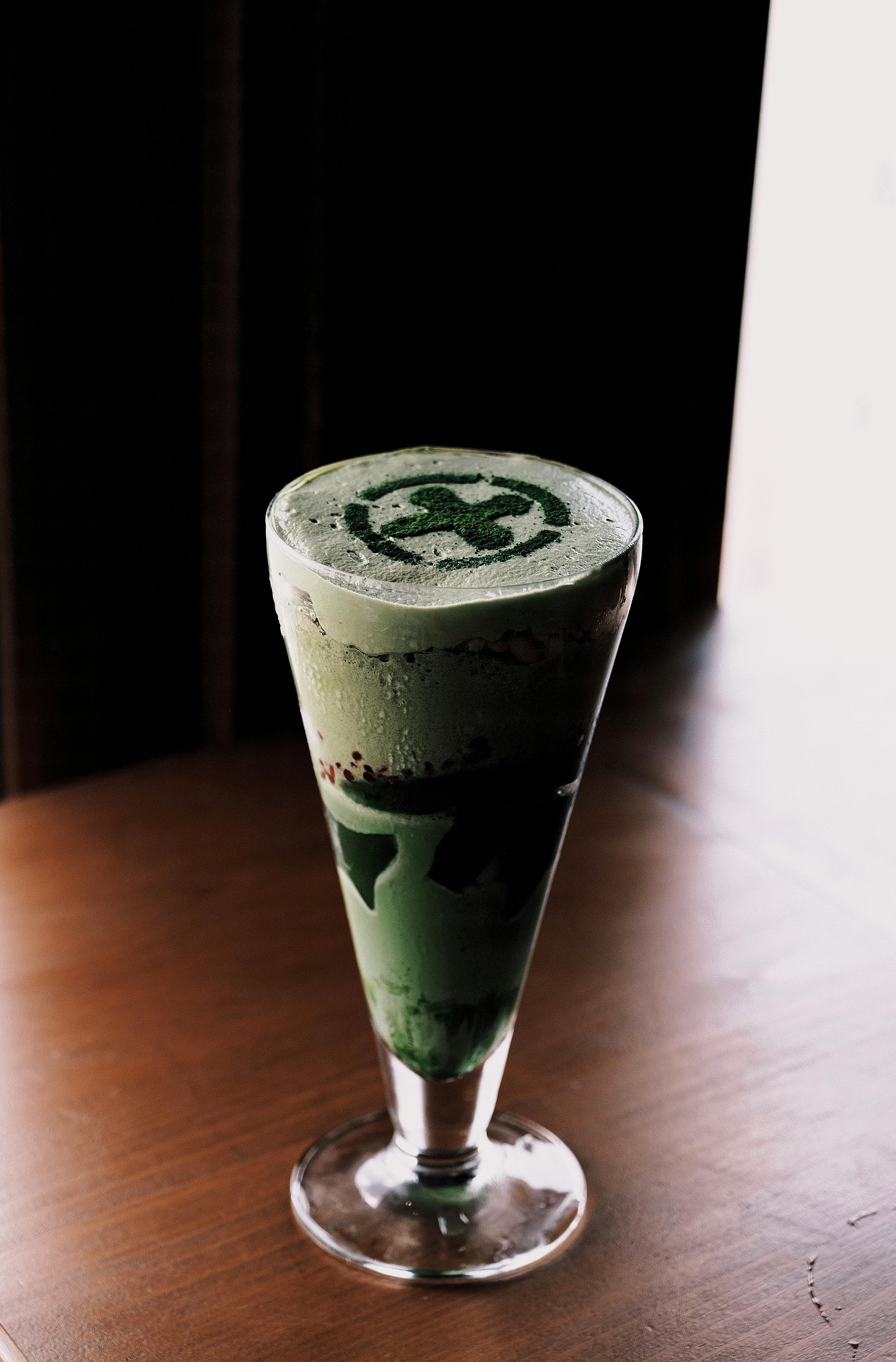 Free A creamy, cold matcha latte with elegant foam art served in a glass on a wooden table. Stock Photo