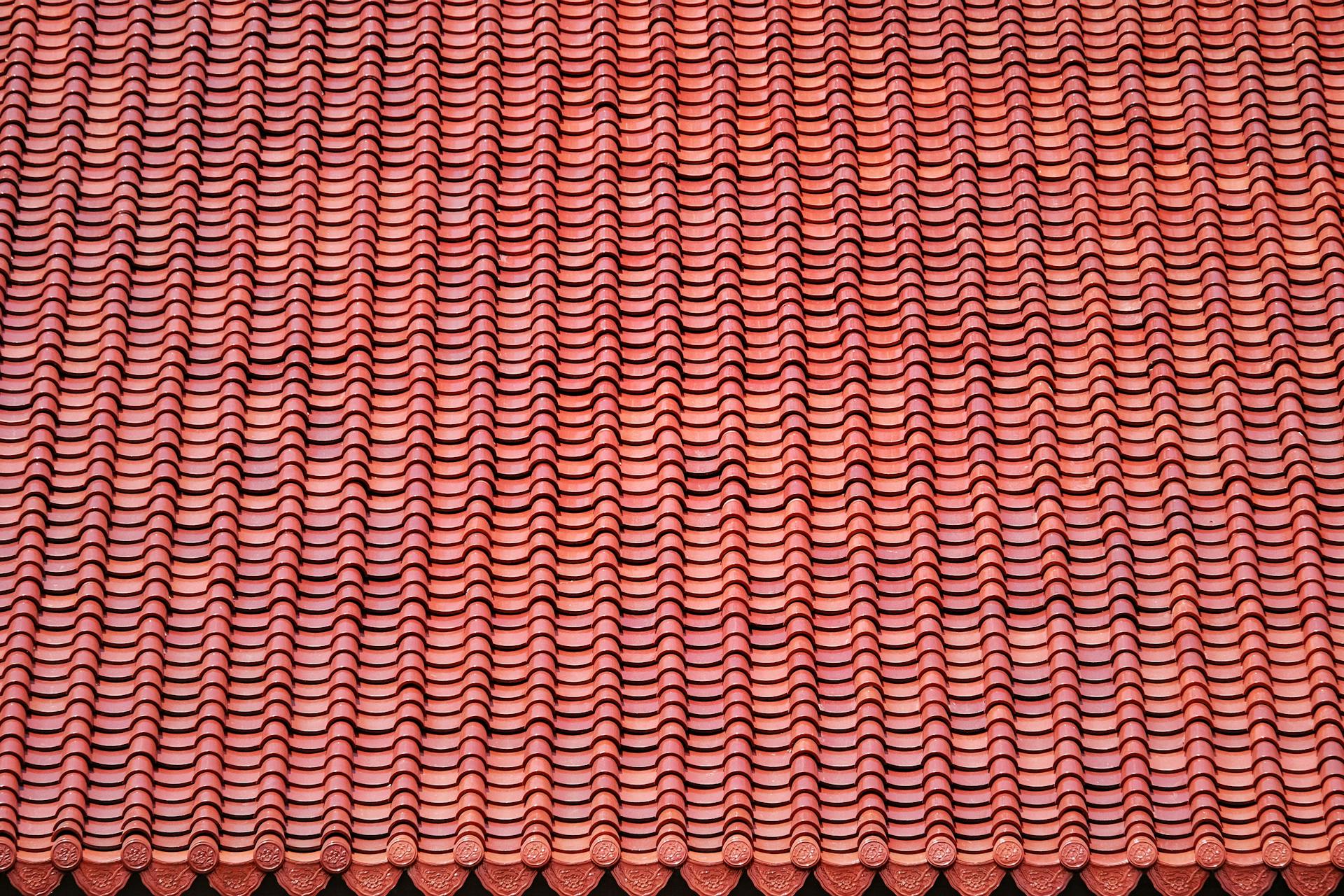 Detailed view of red ceramic roof tiles creating a repetitive pattern.