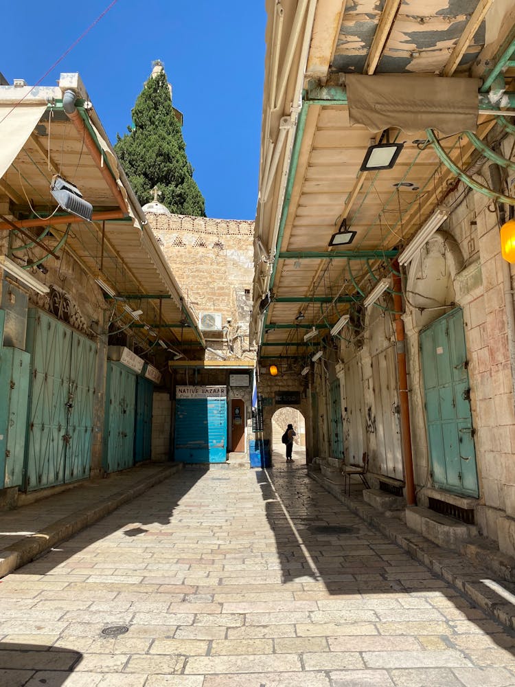 Person Standing In An Empty Market Alley With Closed Shops