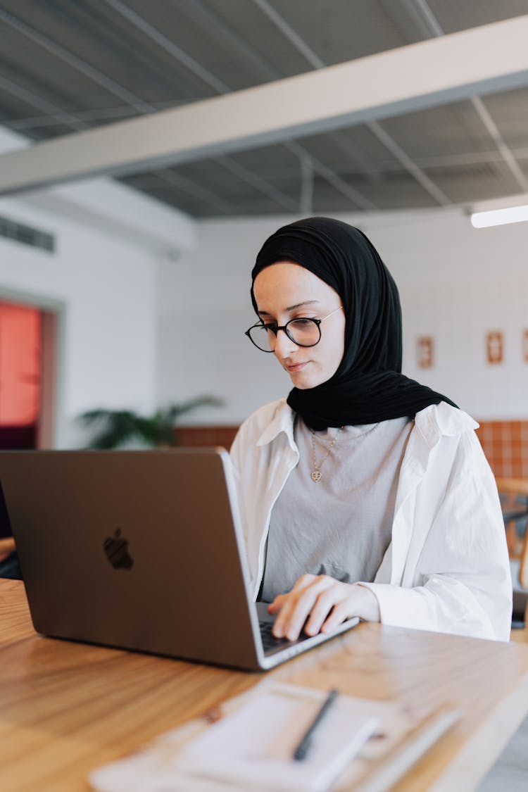 Young Woman Sitting At The Table And Using A Laptop 