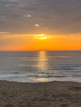 Captivating beach sunset with golden hues reflecting on calm ocean waves.
