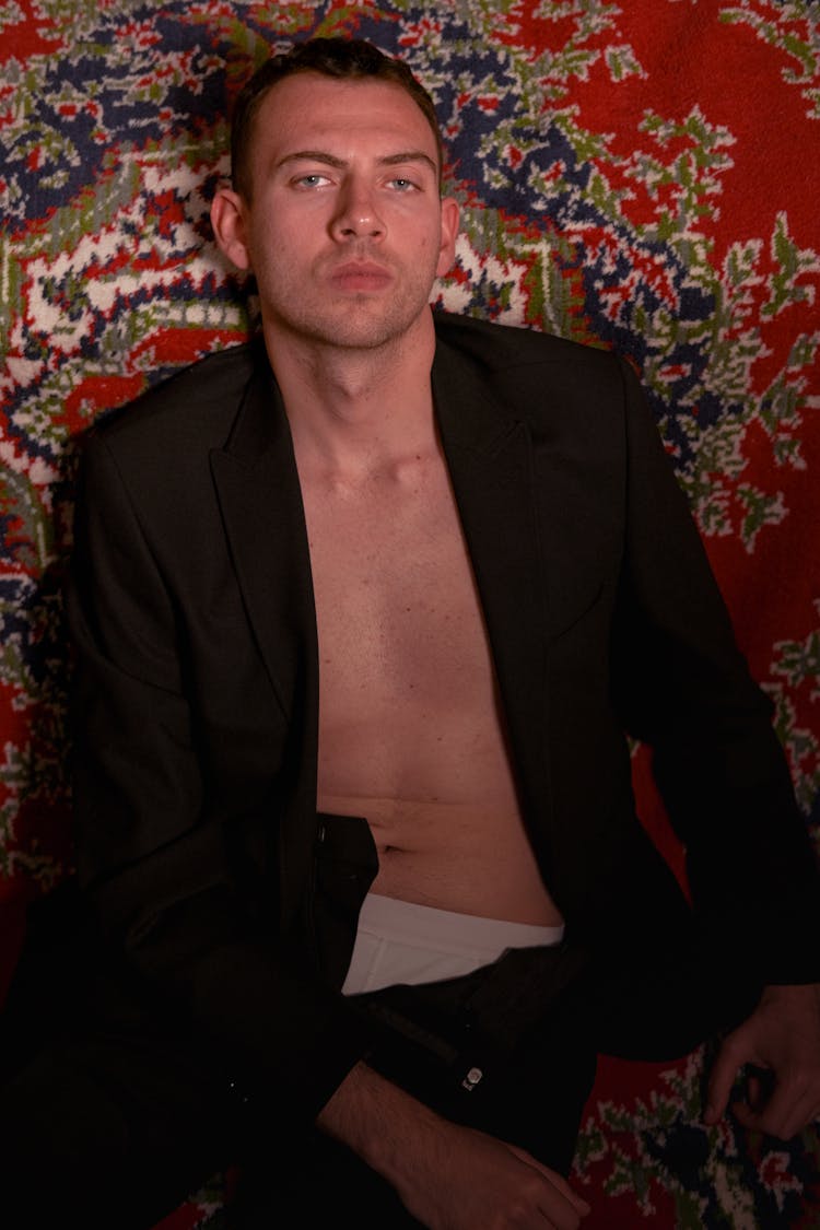 Young Shirtless Man In Black Blazer Lying On A Carpet