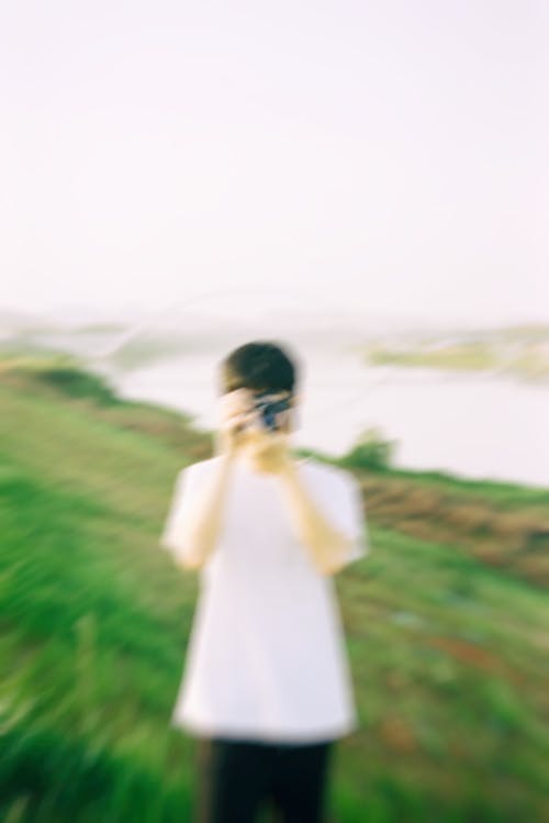Blurry Picture of a Young Man Taking a Picture with a Camera on a Field 