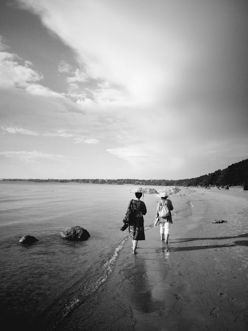 Couple Walking with Umbrellas on Sea Shore in Black and White