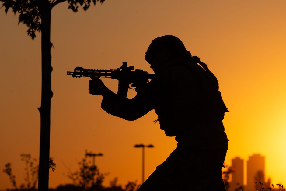 Dramatic silhouette of a soldier with a rifle against a sunrise backdrop.