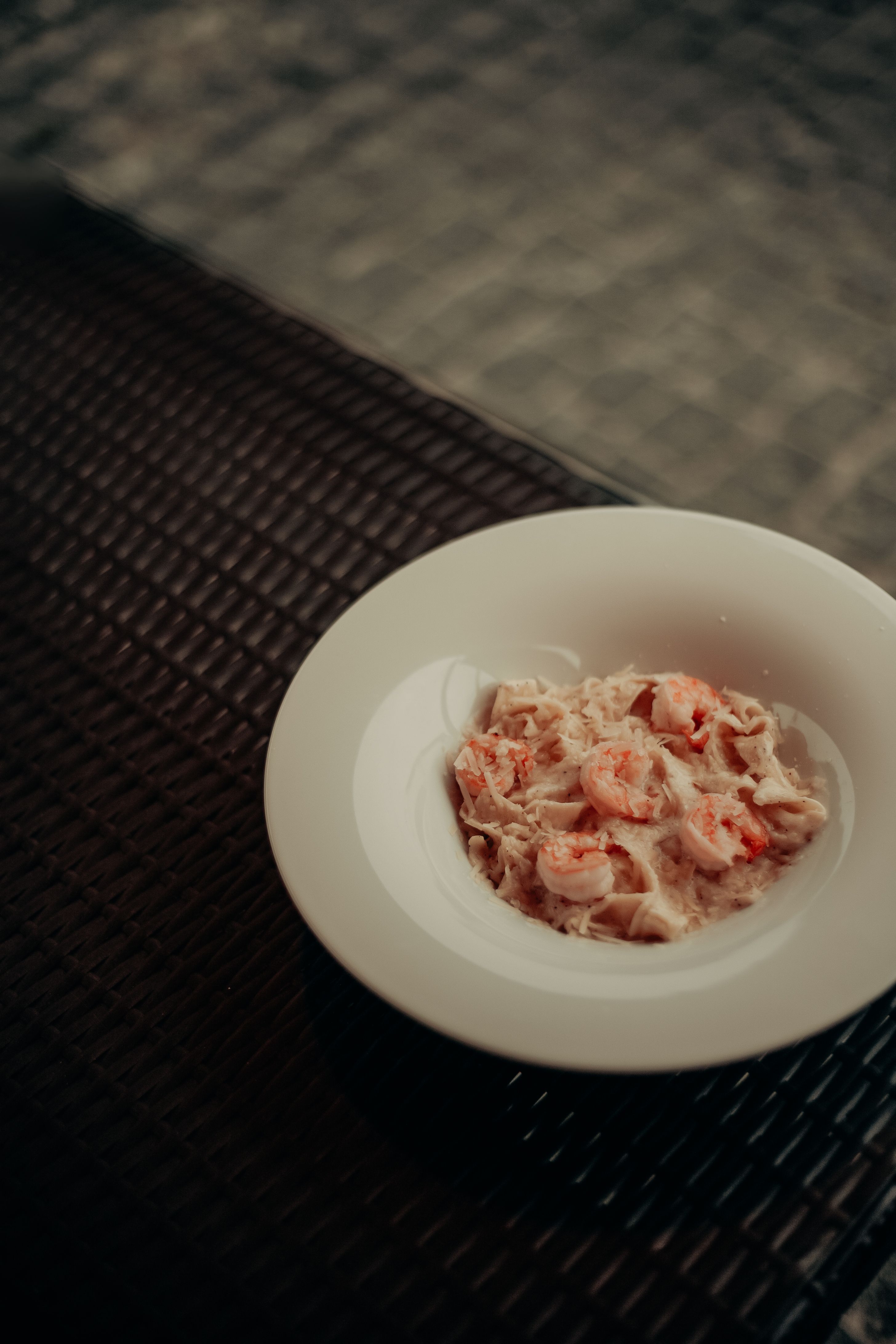 Appetizing creamy shrimp pasta served in a white bowl on a textured surface.