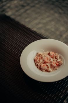 Appetizing creamy shrimp pasta served in a white bowl on a textured surface.