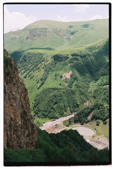 Lush green mountains and valley landscape with reservoir during summer.