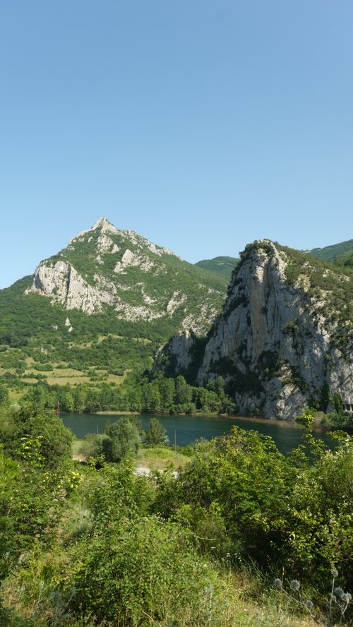 Free Explore a breathtaking mountain landscape with a tranquil river in vibrant summer greens. Stock Photo