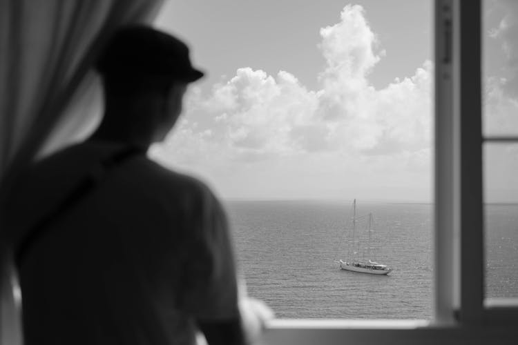 A Man Looking At The Sea From The Window 