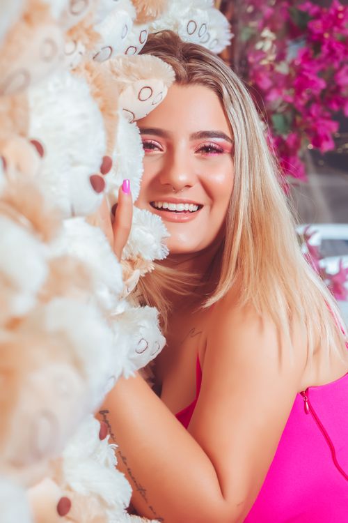 Free Caucasian woman smiling joyfully while hugging a teddy bear wall indoors. Stock Photo