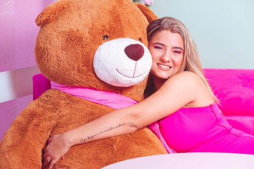 Free A happy young woman embraces a large teddy bear, creating a joyful and playful scene. Stock Photo