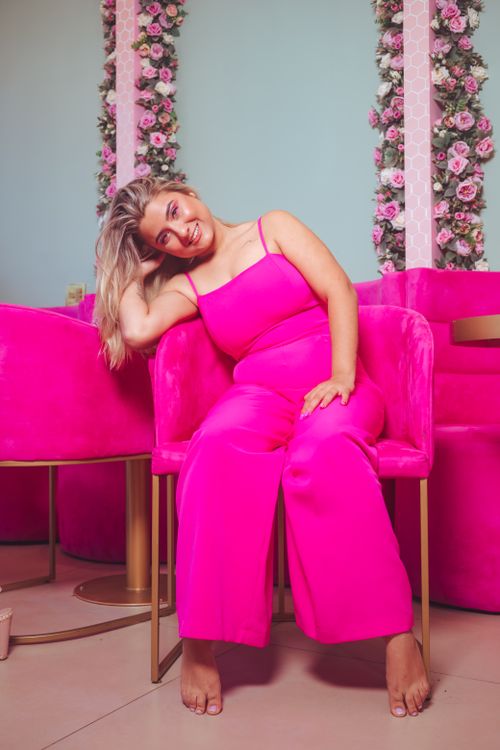 Free Model in pink outfit posing barefoot in a stylish, flower-decorated interior. Stock Photo
