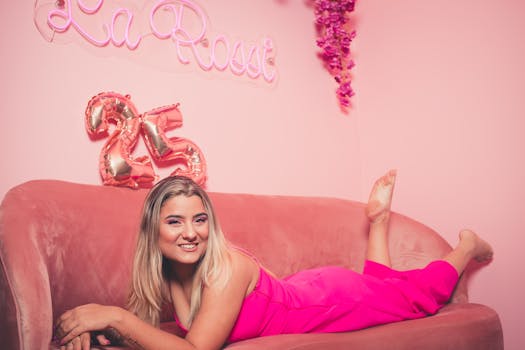 Young woman celebrating 25th birthday surrounded by pink decor and balloons.