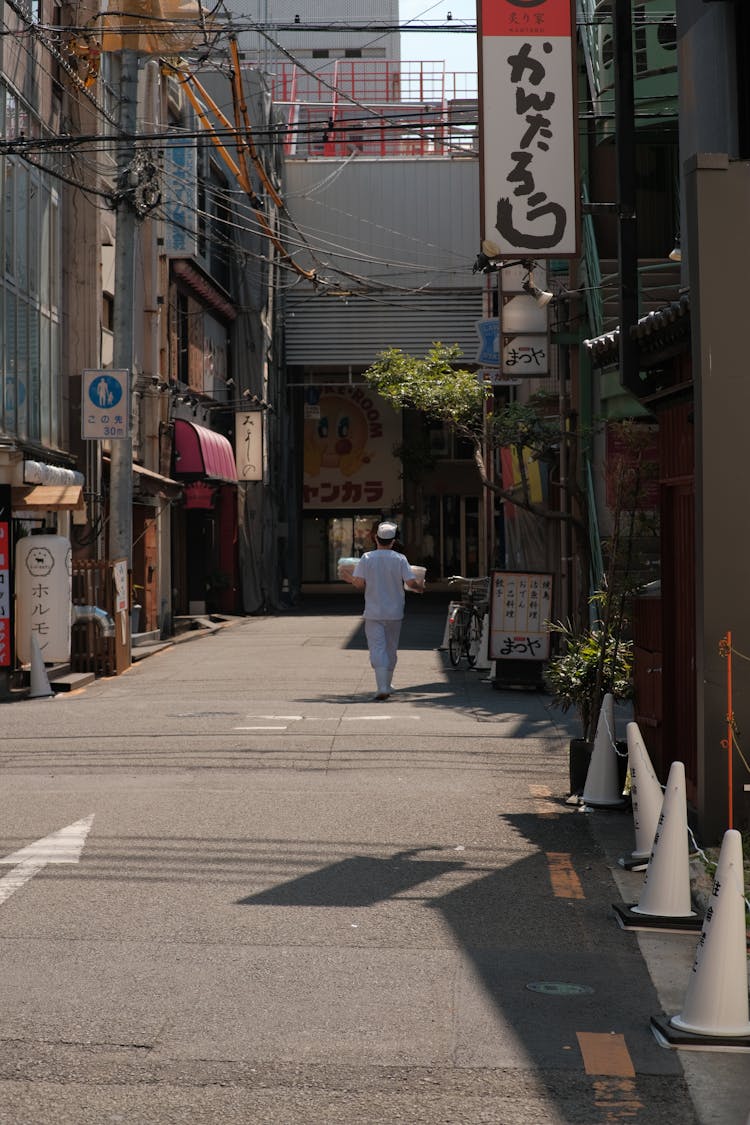 Baker Walking Down Empty Street With Delivery