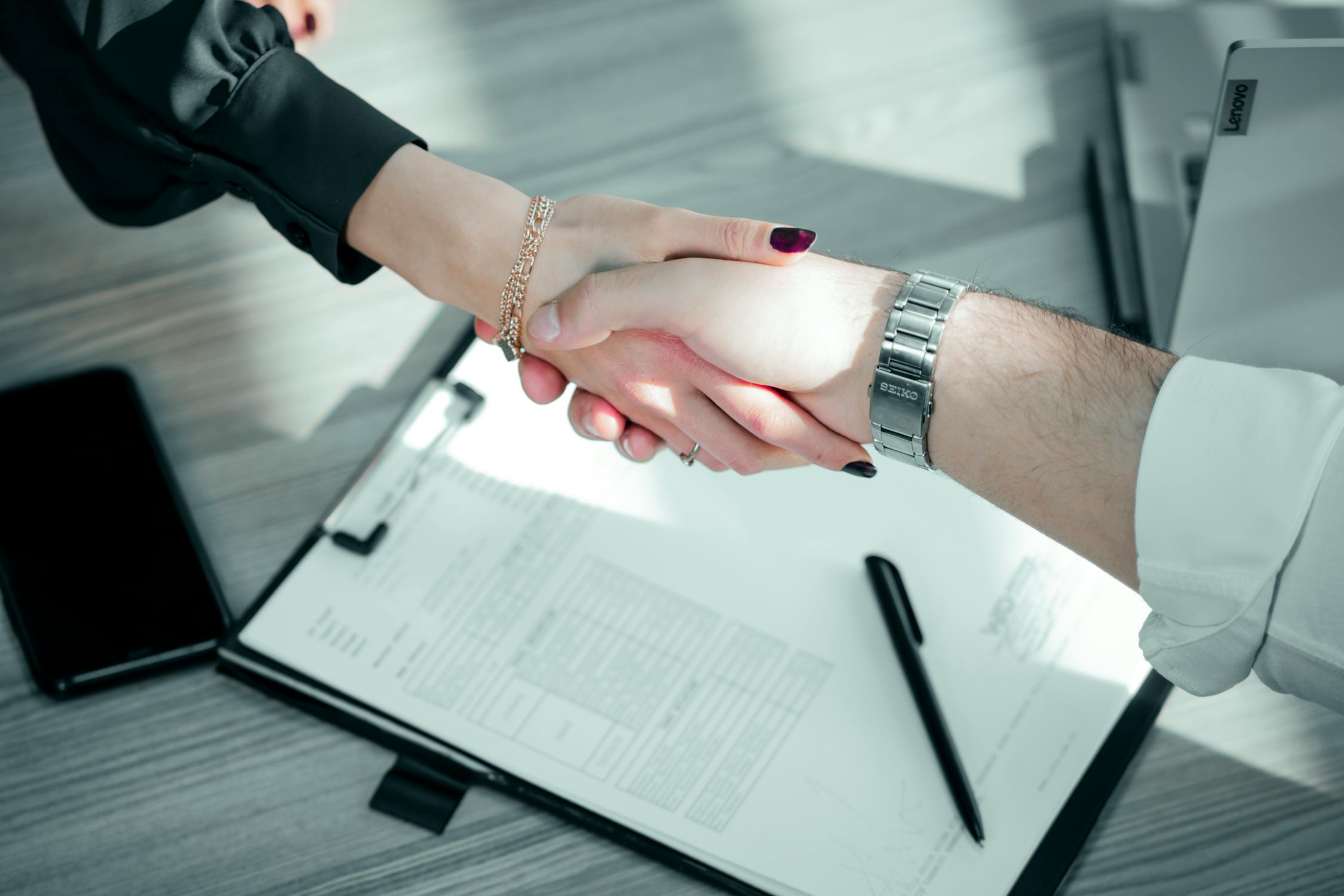Business owner and loan agent shaking hands after finalizing a loan agreement.