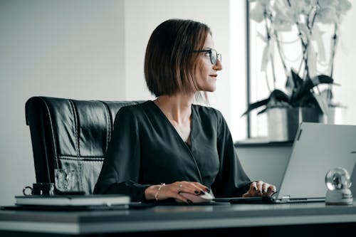 Woman Sitting by Desk Working on Laptop