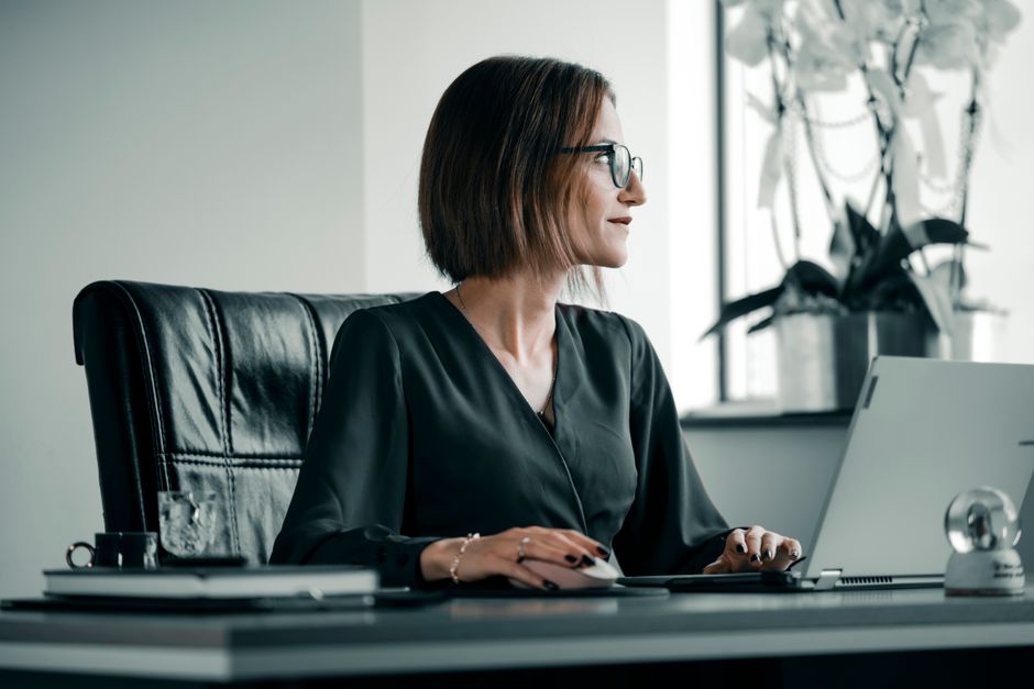 A woman sitting at her desk, deep in thought, looking overwhelmed by paperwork A woman sitting at her desk, deep in thought, looking overwhelmed by paperwork