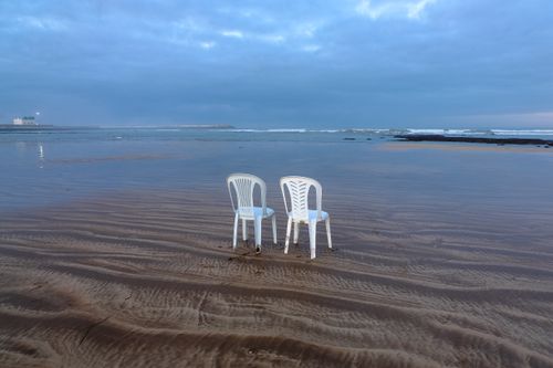 Free Two empty chairs on a tranquil beach at El Jadida, Morocco during a serene sunset. Stock Photo