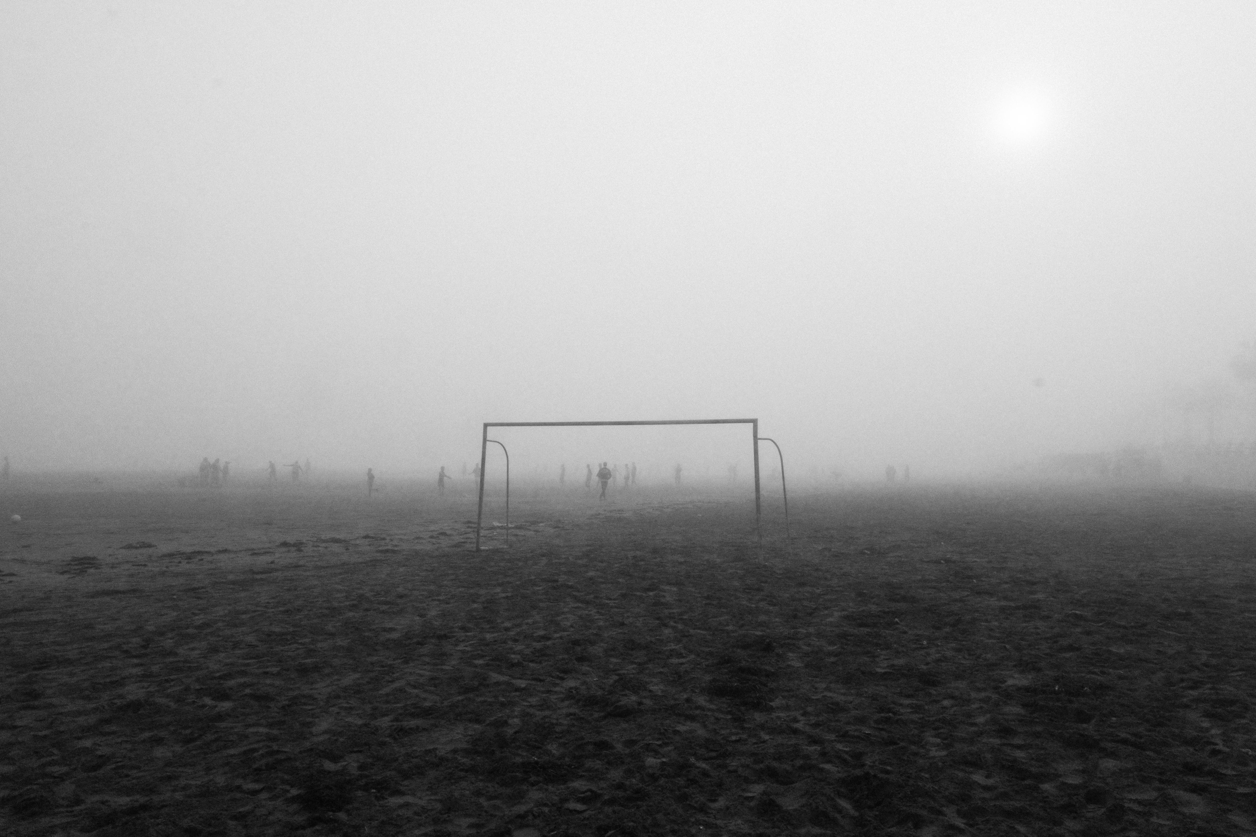 Foggy soccer field with players in El Jadida, Morocco, creating a mysterious atmosphere.