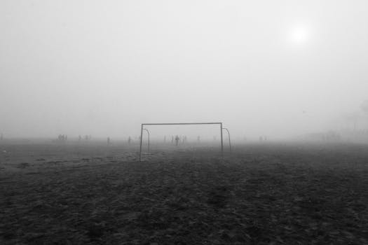 Foggy soccer field with players in El Jadida, Morocco, creating a mysterious atmosphere.