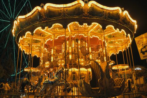 Free An ornate carousel brightly lit up at night, creating a magical atmosphere in an amusement park. Stock Photo