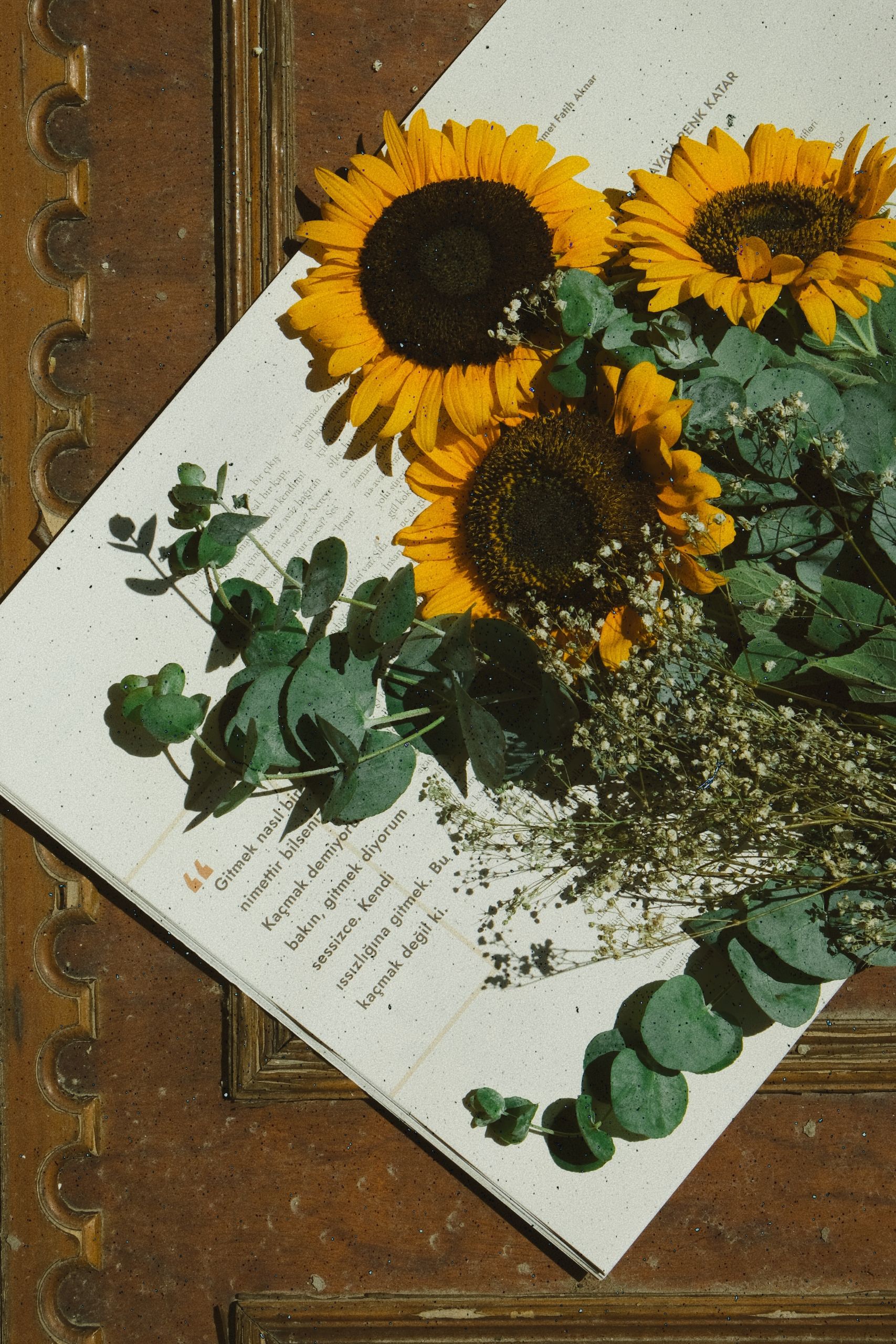 Aesthetic composition of sunflowers and greenery on an open book, creating a rustic, vintage feel.