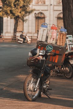 Motor scooter with ice cream vending setup on an urban street corner in daylight.