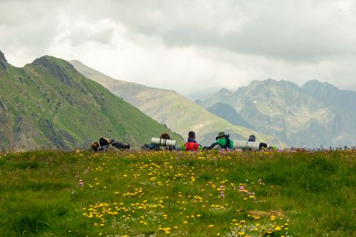 Free A group of hikers resting on a lush mountain meadow with a panoramic view of distant peaks. Stock Photo