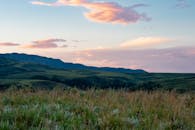 日落时分，起伏的山丘风景如画，前景是充满活力的天空和草原