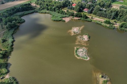 Free Expansive aerial view of a tranquil lake surrounded by greenery and small islands. Stock Photo