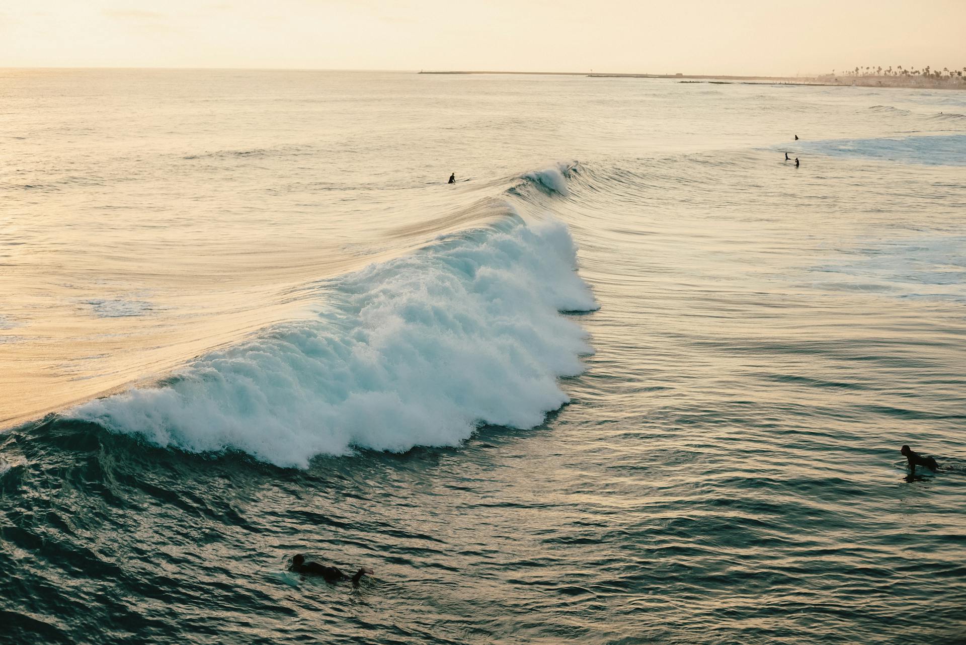 Surfers catch waves on a scenic California coastline at sunset, perfect for adventure and travel imagery.