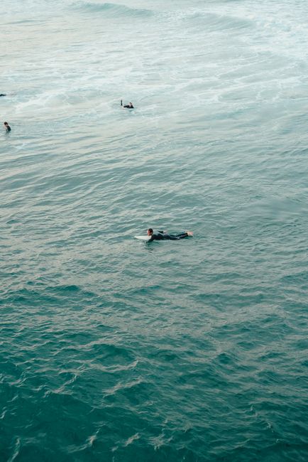 Surfers enjoying the ocean waves in a scenic coastal setting, perfect for adventure lovers.