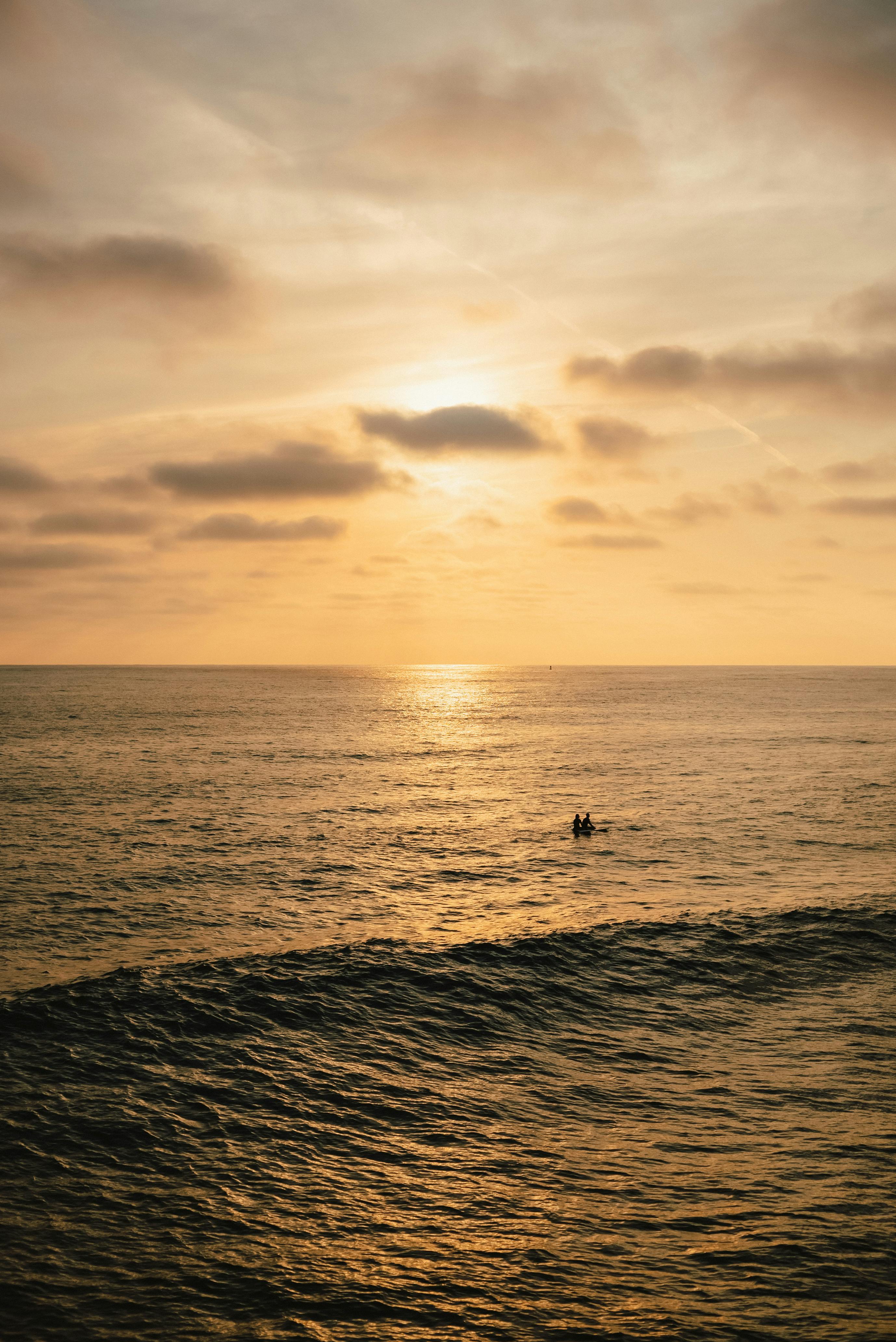 a surfer is in the ocean at sunset