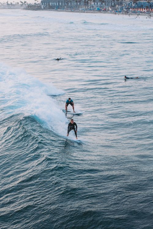 Free Surfers riding waves at a popular coastline destination, capturing the thrill and beauty of the ocean. Stock Photo