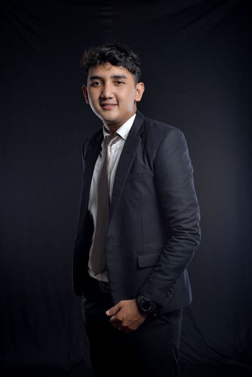 Free Smiling man in a stylish black suit posing confidently in a studio setting. Stock Photo