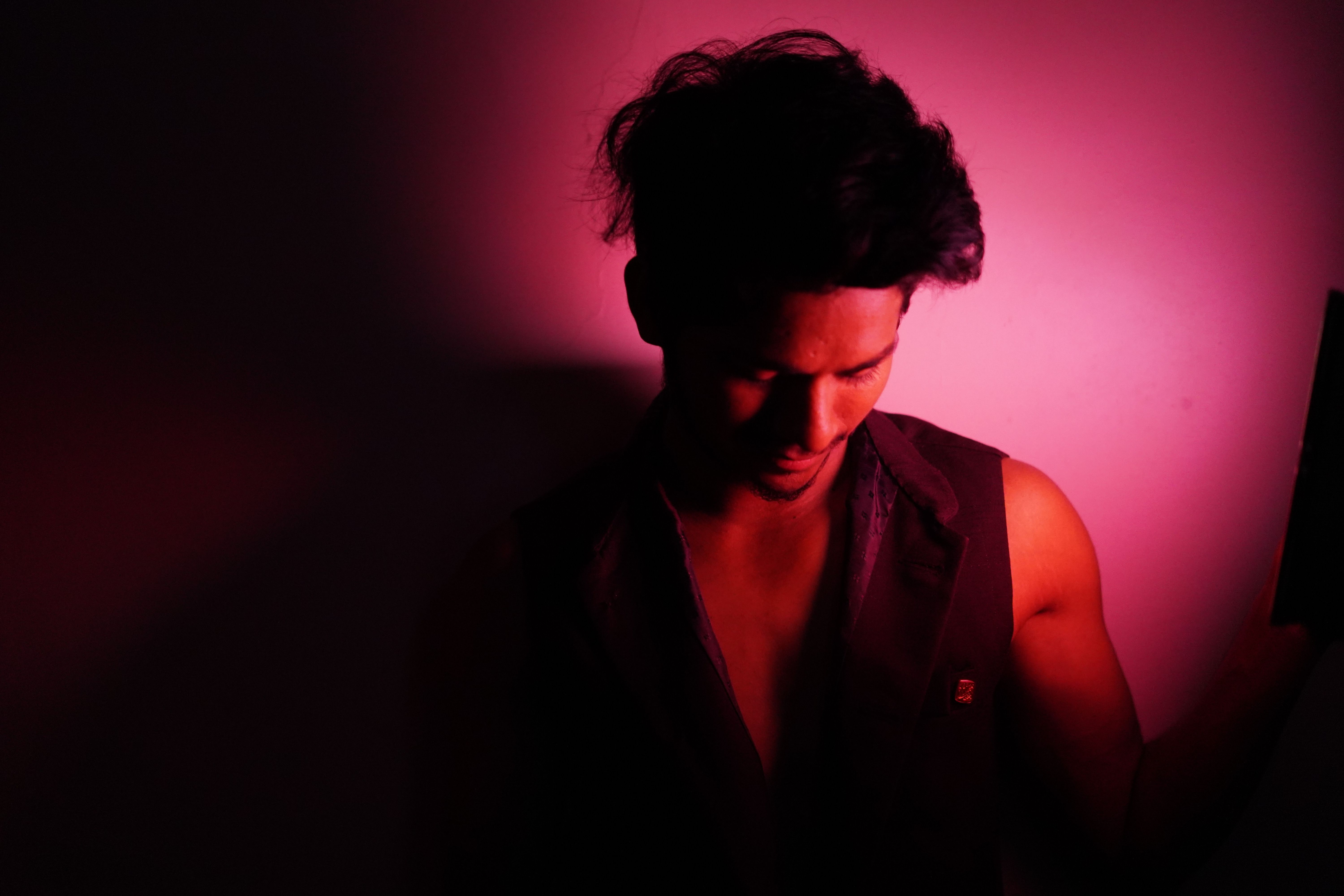 A moody portrait of a man bathed in vibrant red light, creating a dramatic effect.