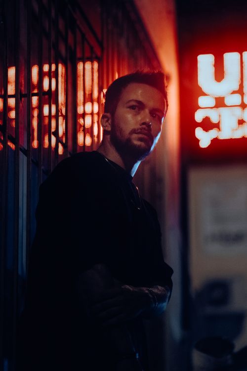 Free Moody night portrait of a man in a neon-lit alleyway, showcasing urban fashion and style. Stock Photo
