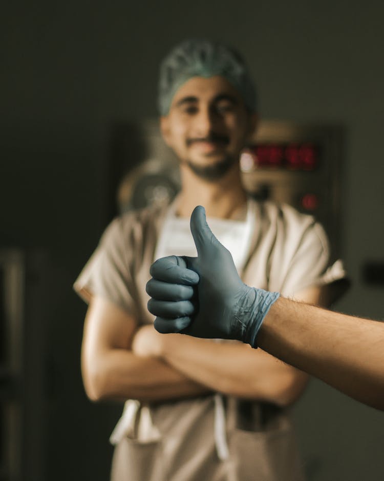 Hand With Thumb Up Over Doctor Standing Behind