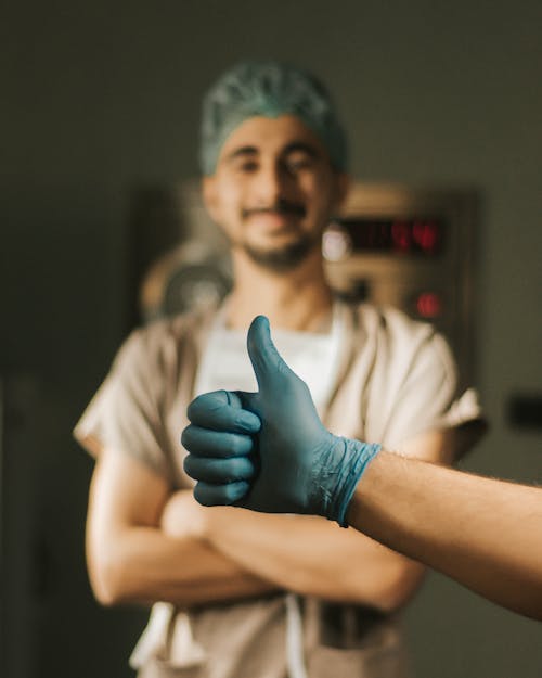 Hand with Thumb Up Gesture over Standing Doctor