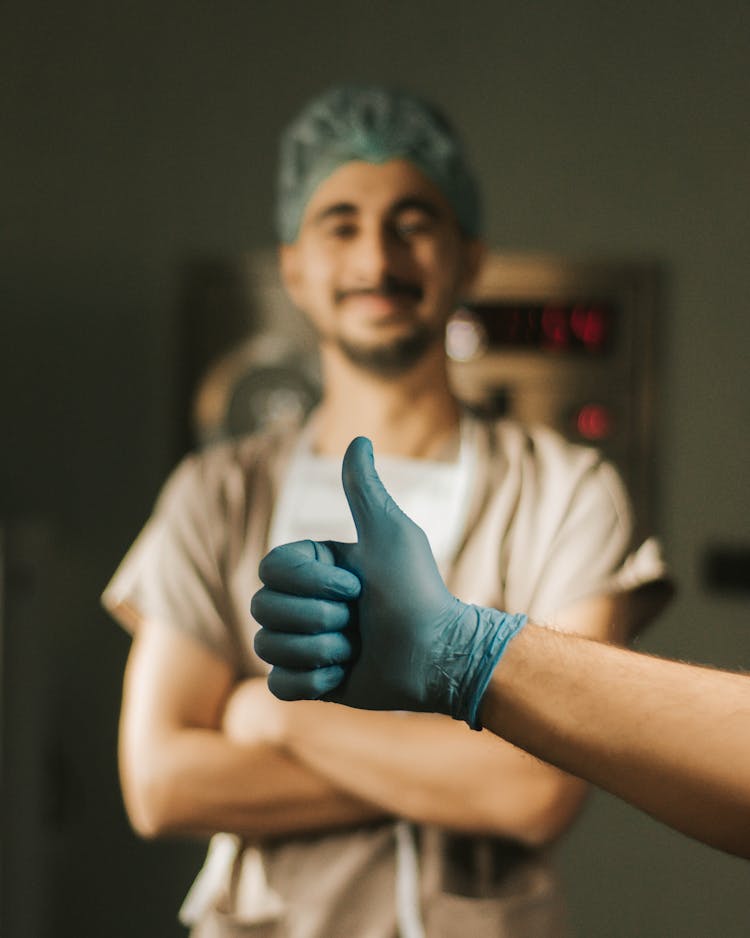 Hand With Thumb Up Gesture Over Standing Doctor