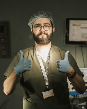 Confident healthcare professional in hospital setting giving a thumbs-up gesture, signifying positivity.
