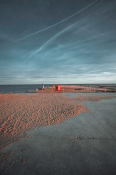 Tranquil view of a beach at dawn in Barcelona with SOS kiosk. Sky and sea meet on the horizon.