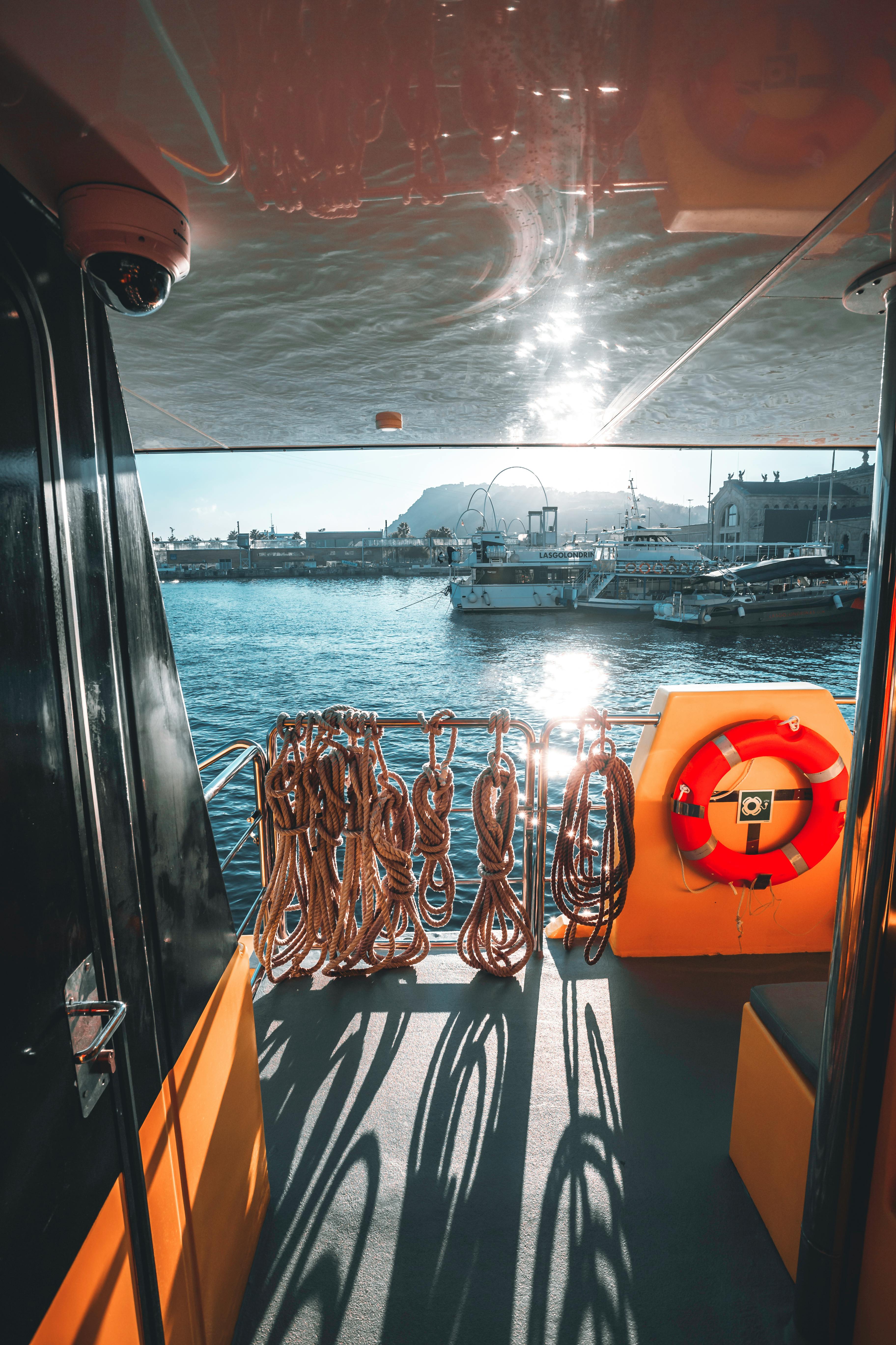 A beautiful Barcelona harbor view from a boat with ropes and life preserver on deck.