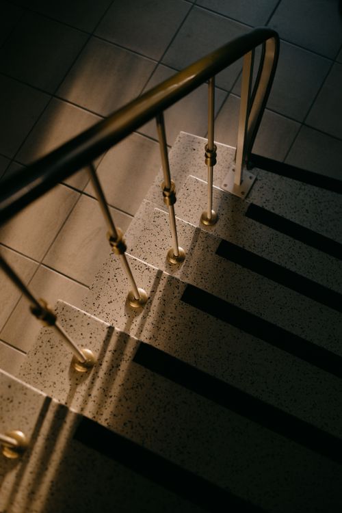 Free A beautifully lit staircase featuring golden handrails and shadows. Stock Photo