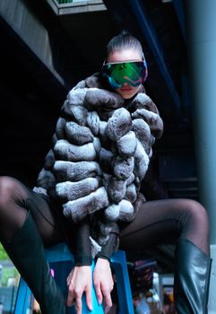 A stylish model poses with fur jacket and futuristic sunglasses, exuding glamour.