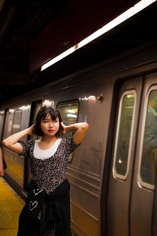 Young Woman Standing in front of a Subway Train 