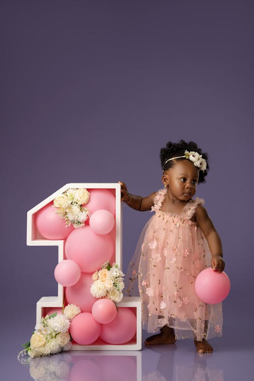 Studio Shot of a Little Girl with a Decoration in a Shape of Number 1 